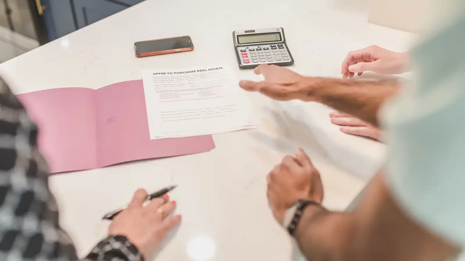 Homebuyers reviewing real estate purchase documents with a calculator before closing.